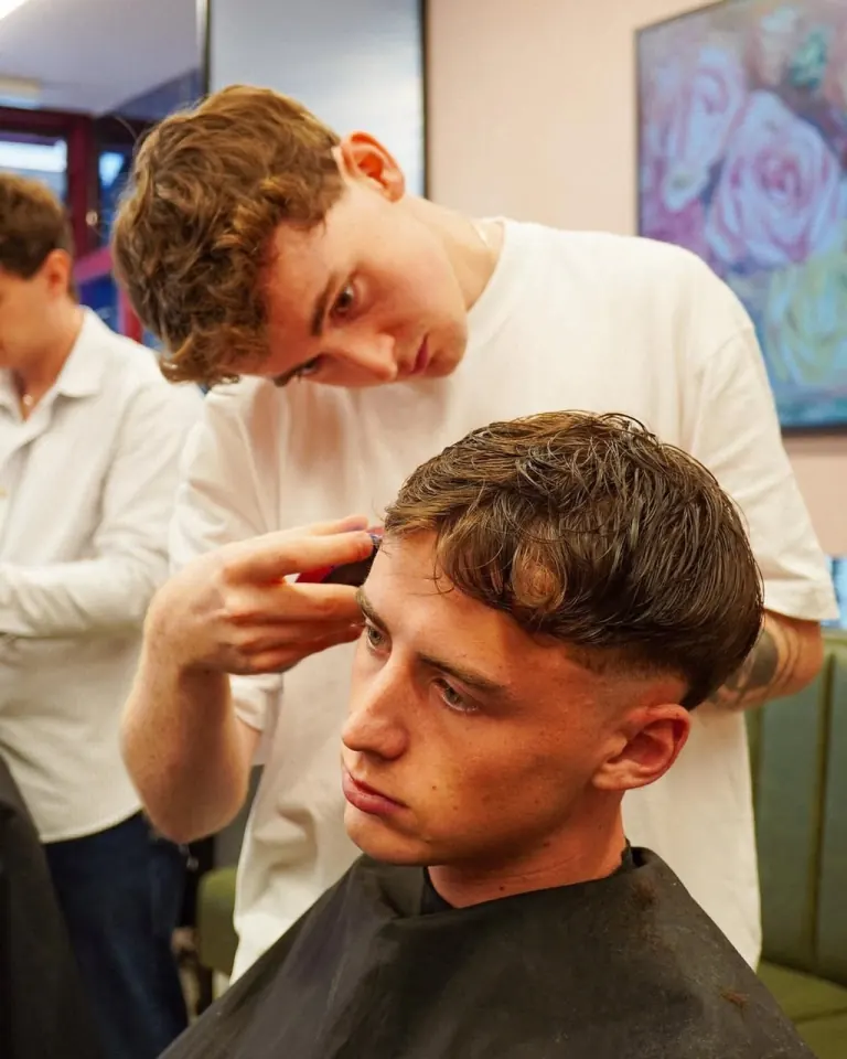 A stylist cutting the sides of a client's hair with scissors