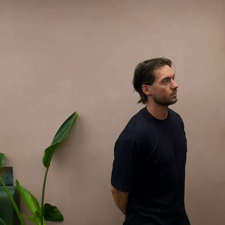 A man in profile with a fresh cut beside a tall plant