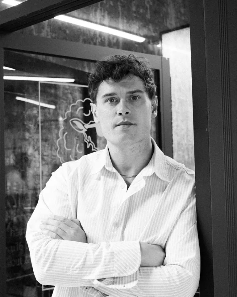 Black and white portrait of Jordan Kerr O'Neill with arms folded in the doorway of Shorn